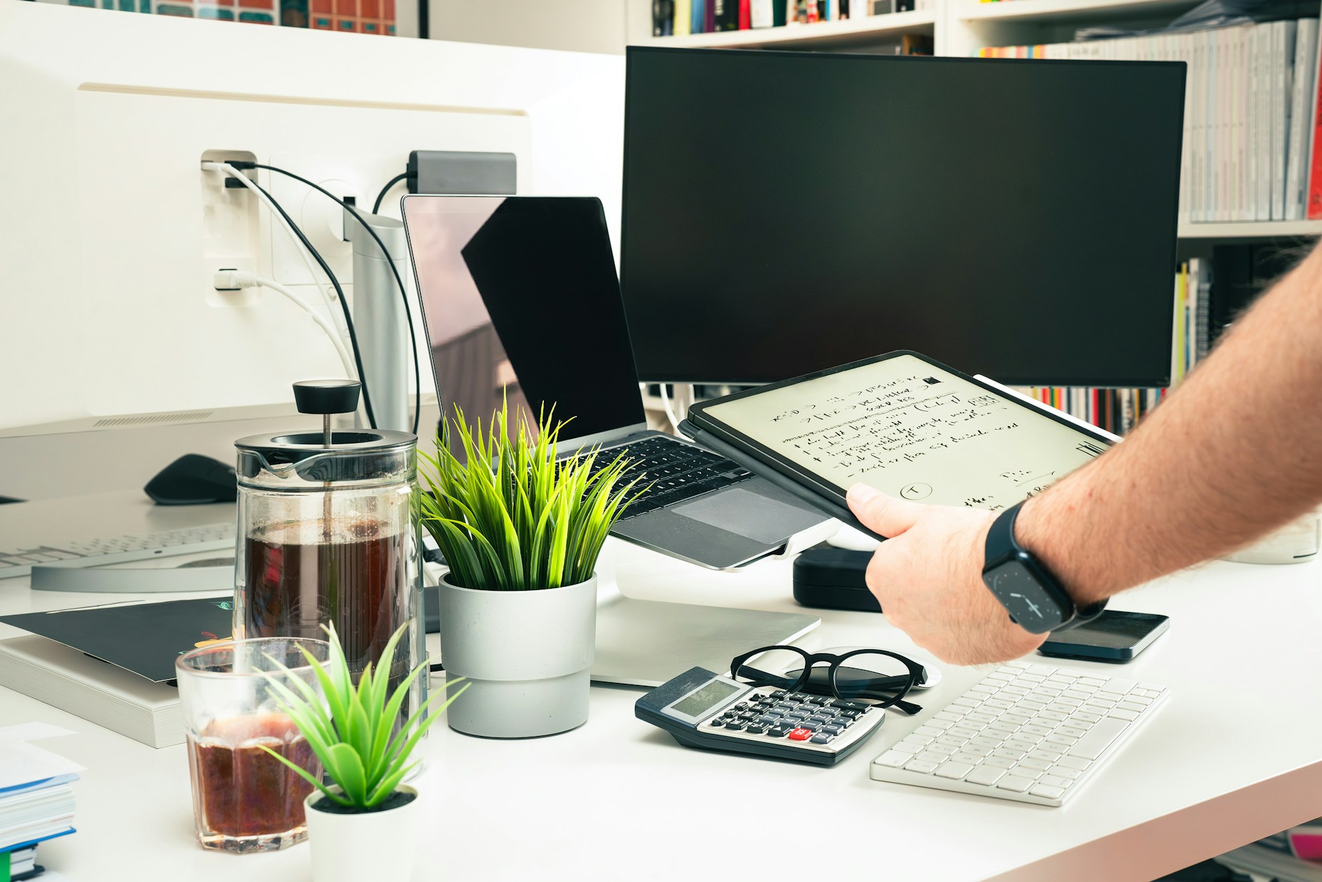 a man is holding a tablet while sitting at a desk